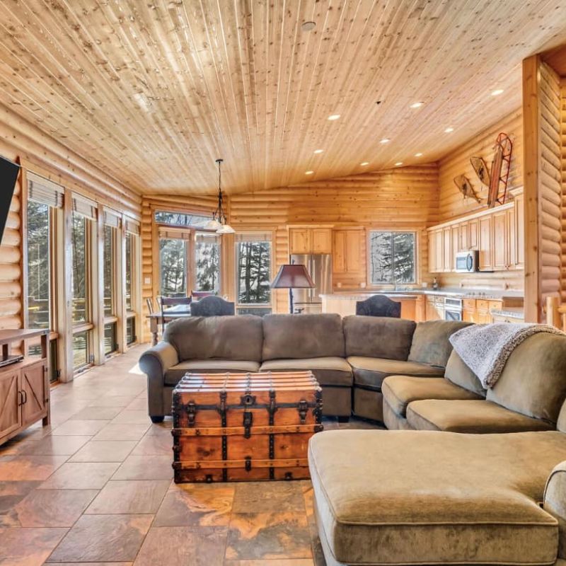 Log cabin great room with sectional sofa, mounted TV, and open kitchen