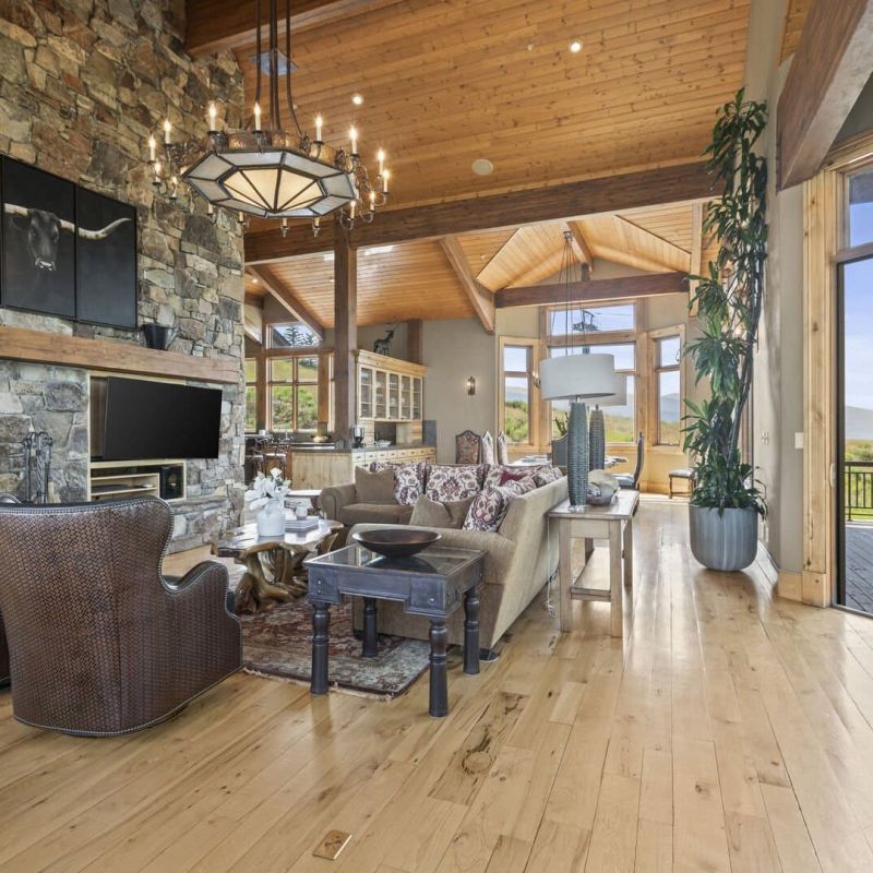 Great room with stone fireplace, wood-beam ceiling, and open deck access