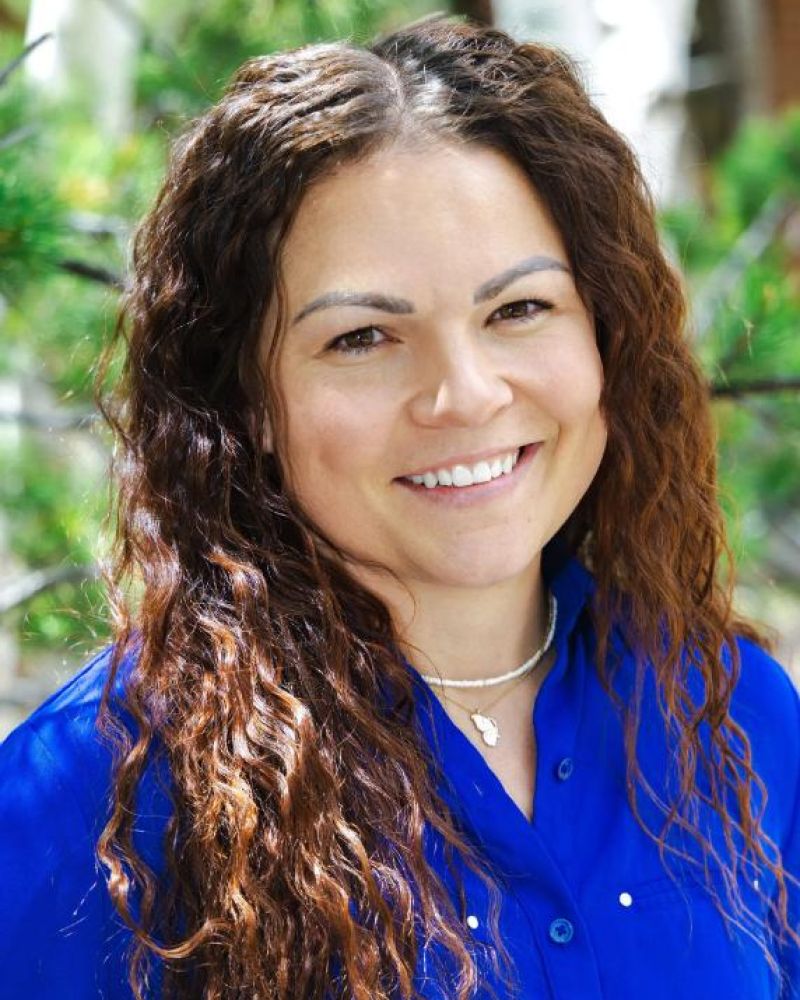 Headshot of a smiling woman in a blue blouse outdoors