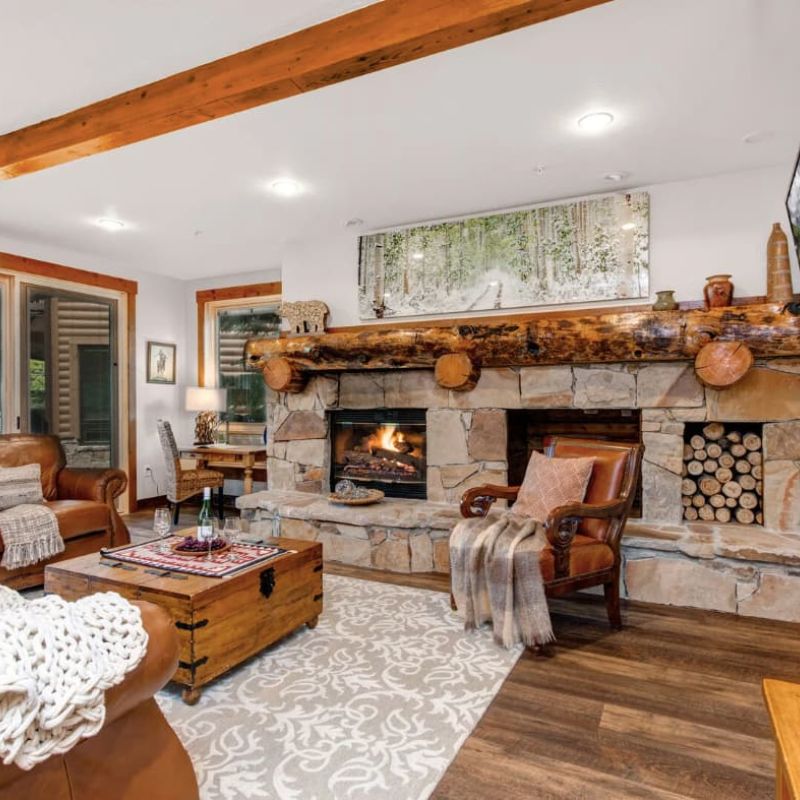 Rustic living room with river-rock fireplace, log mantel, and mounted TV
