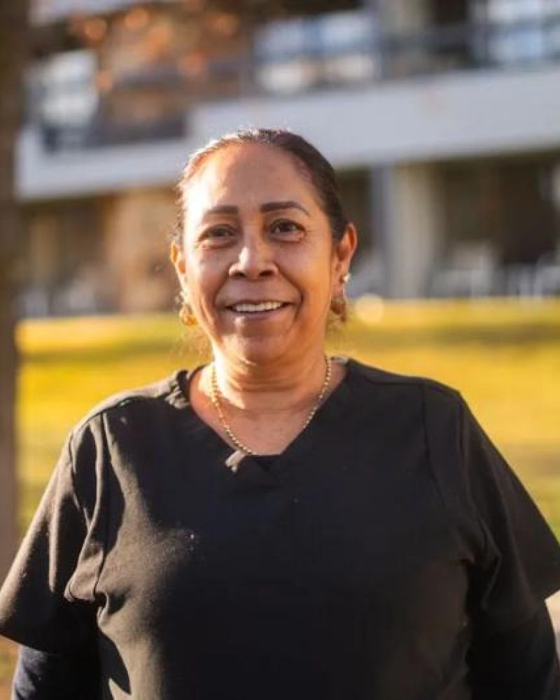 Headshot of a smiling woman in a black shirt outside a building