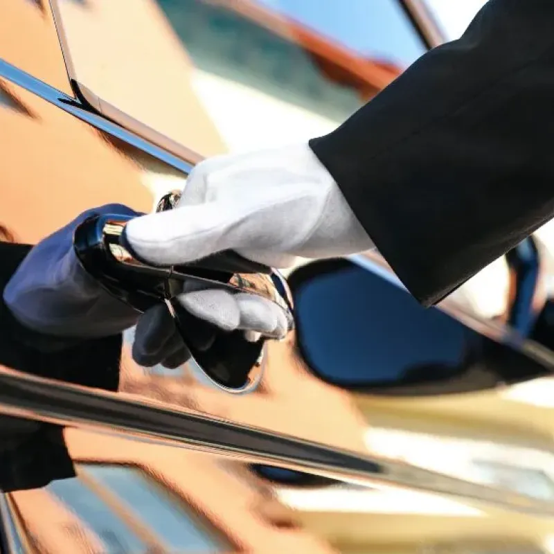 Gloved chauffeur opening the door of a black town car