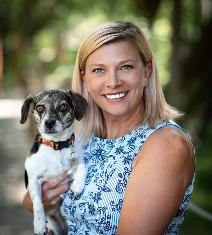 Smiling woman holding a small black and white dog outdoors