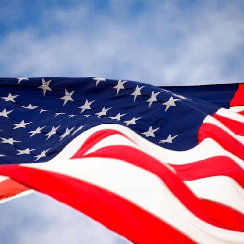 American flag waving against a partly cloudy blue sky