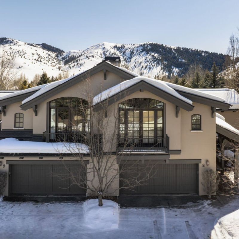 Snow-covered mountain duplex with arched windows and snowy peaks behind