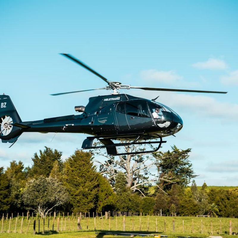Black Heletranz helicopter hovering above a rural landing field