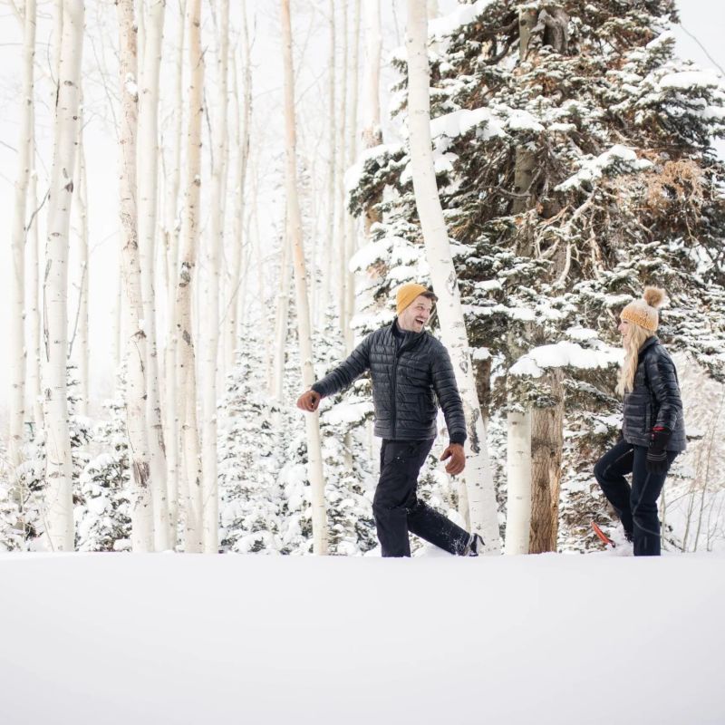 Couple walking through deep snow among aspen trees in winter