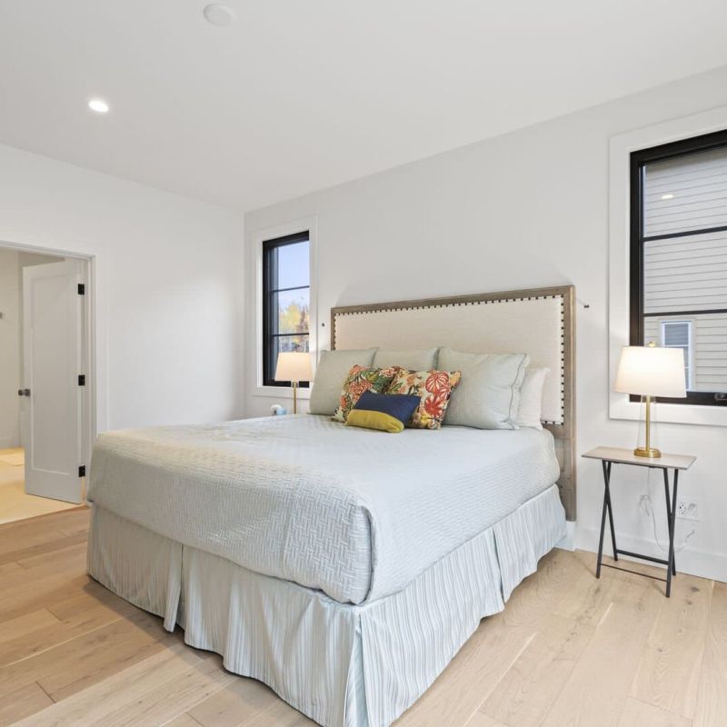 Bedroom with upholstered headboard, queen bed, and white oak floors