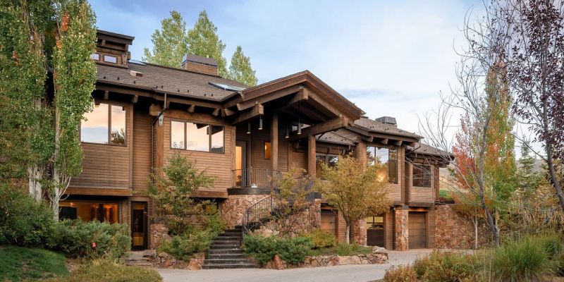Timber-and-stone mountain home exterior with paver driveway at dusk