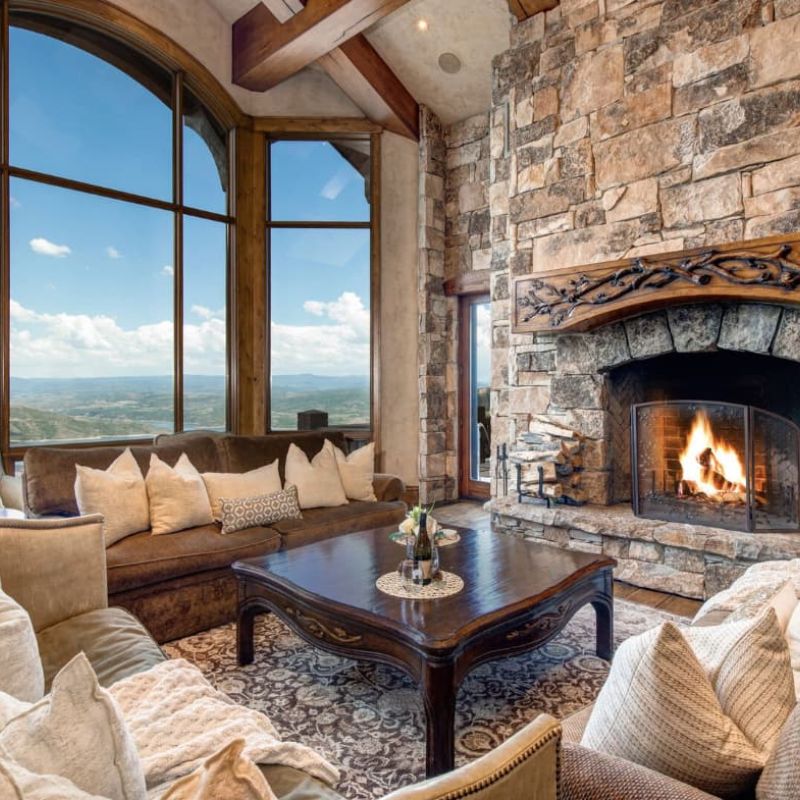 Living room with stone fireplace and arched window framing mountain views