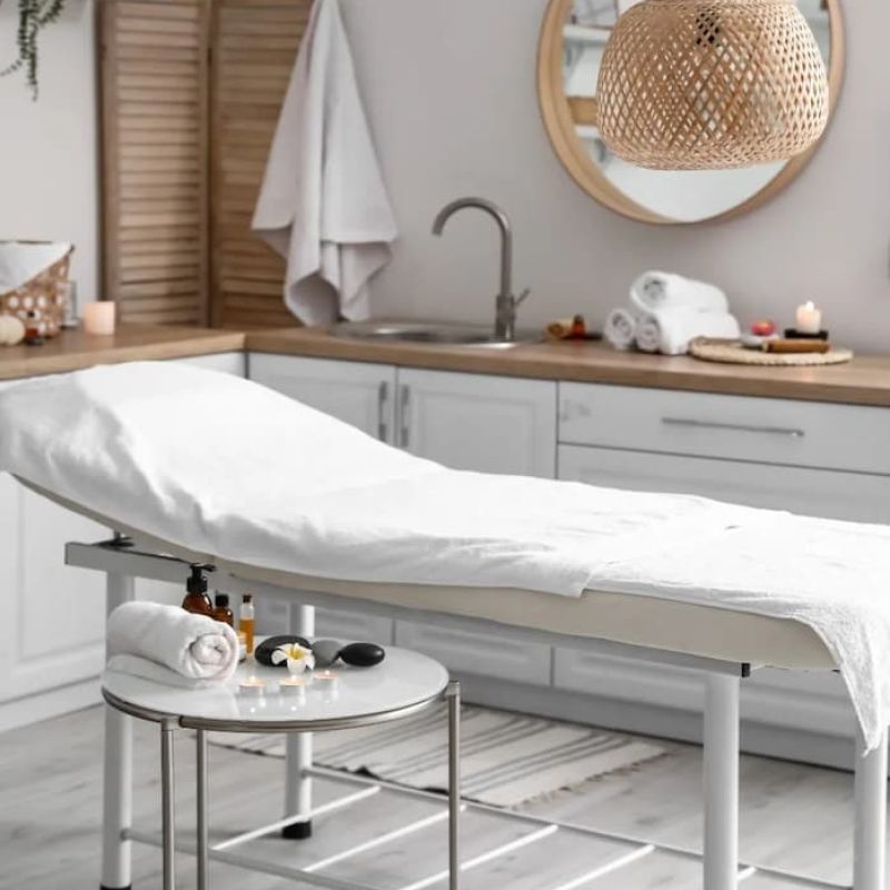 Spa treatment room with a draped massage table and round mirror