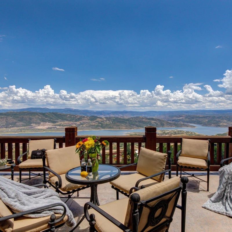 Mountaintop deck with patio chairs and table overlooking Jordanelle Reservoir and Wasatch range