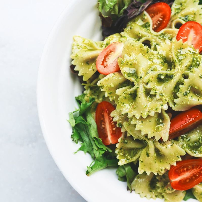 Bowtie pasta with pesto and cherry tomatoes on greens