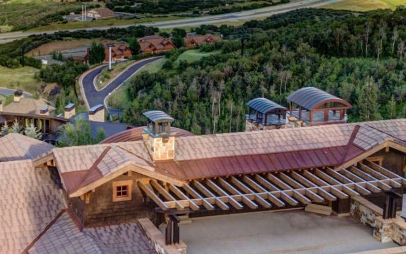 Aerial view of a stone-and-timber luxury home overlooking a mountain reservoir near Park City, Utah