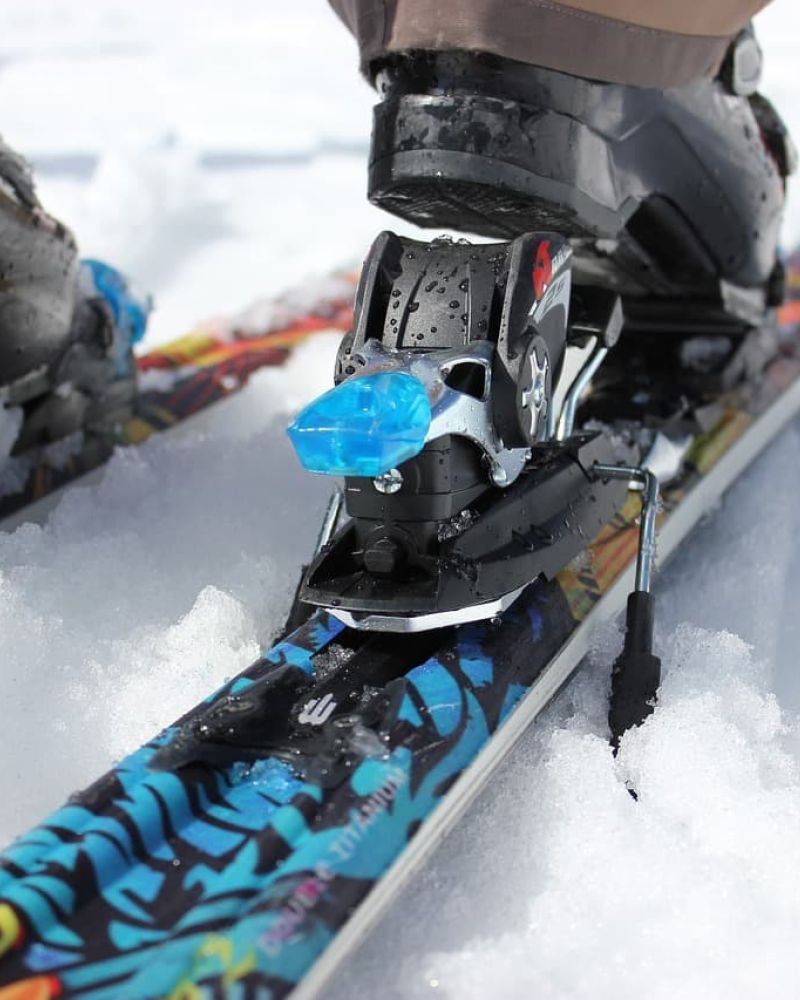 Close-up of ski boot clicked into a colorful ski binding in fresh snow
