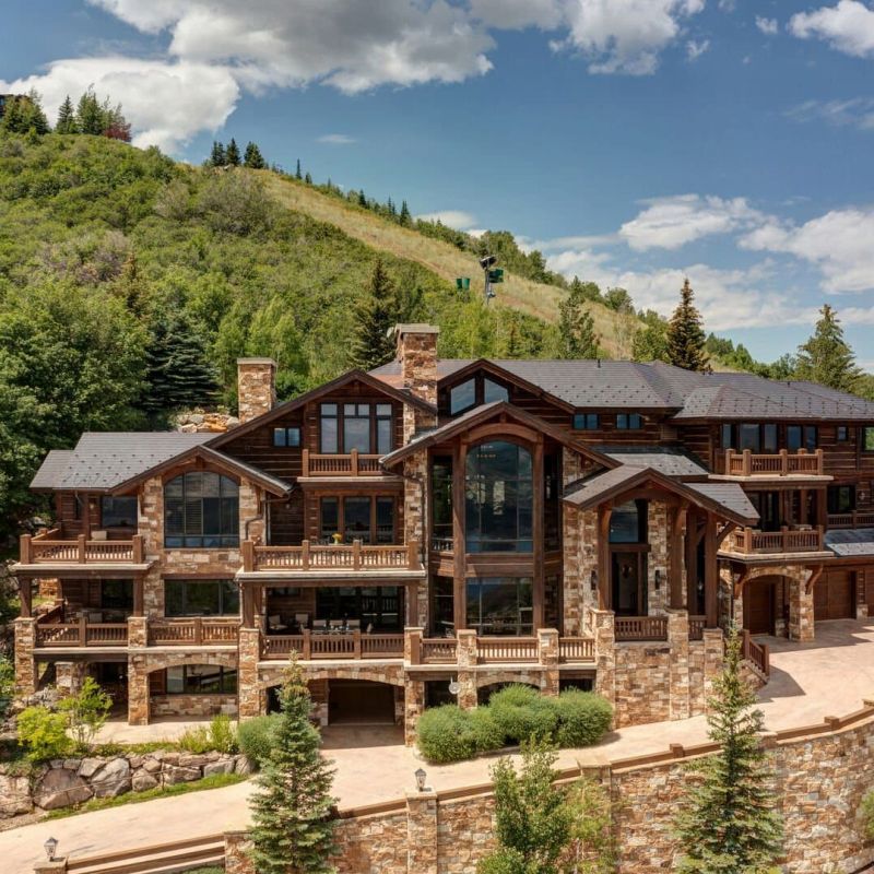 Aerial view of stone-and-timber mountain estate on a forested hillside