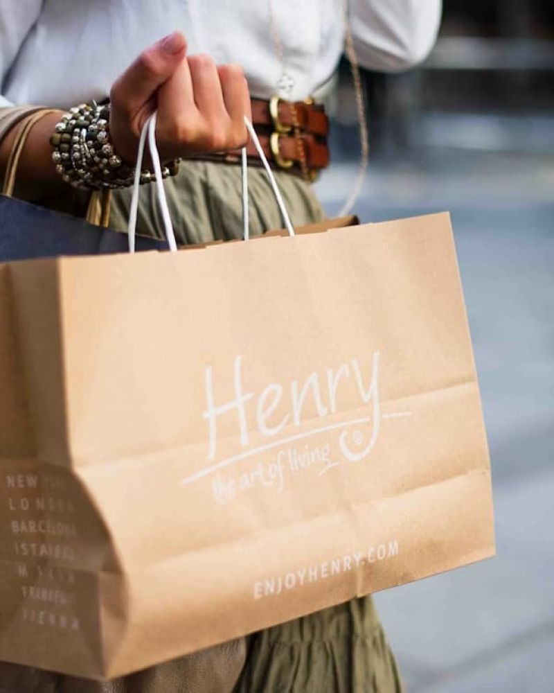 Shopper carrying paper bags including one labeled Henry the art of living