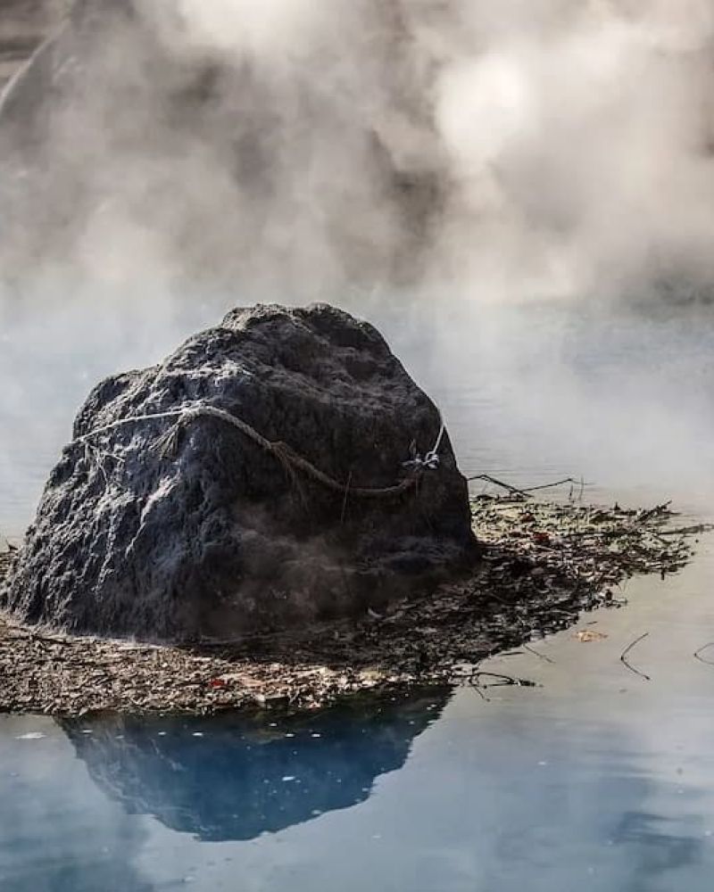 Steam rising from a rock in a natural hot spring pool