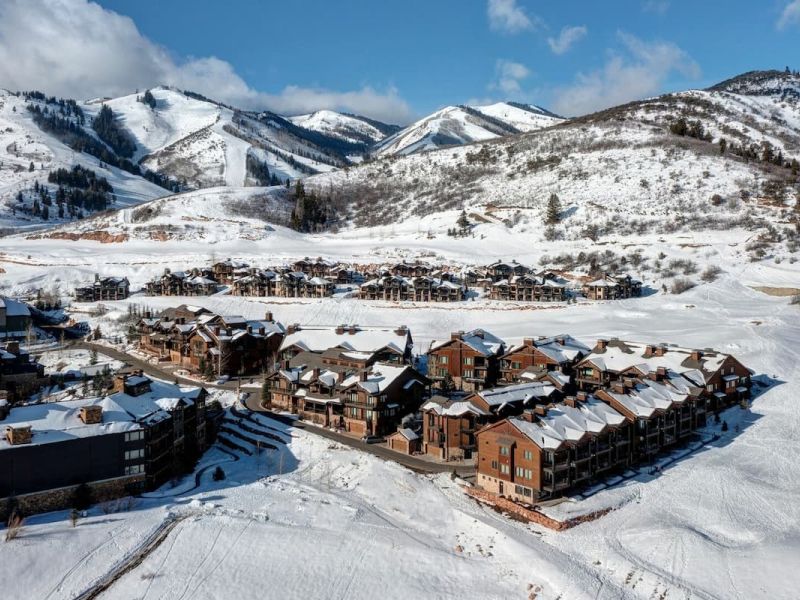 Aerial view of a Park City slopeside neighborhood with snow-covered ski runs in the background