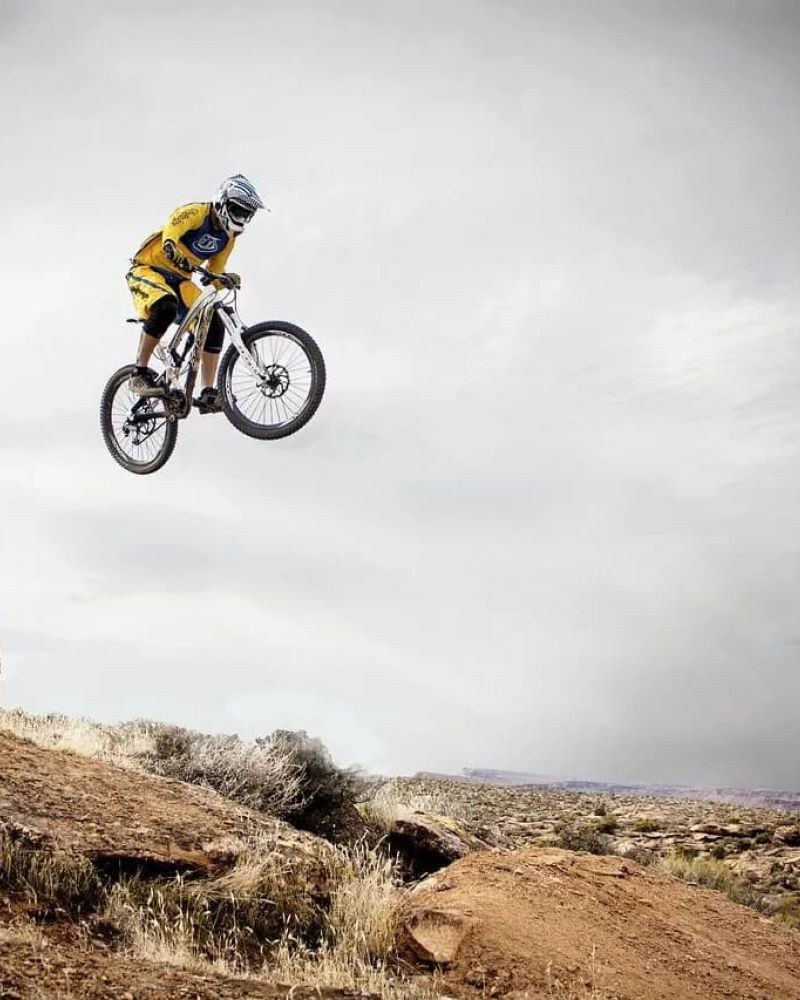 Mountain biker catching air off a desert ridge jump