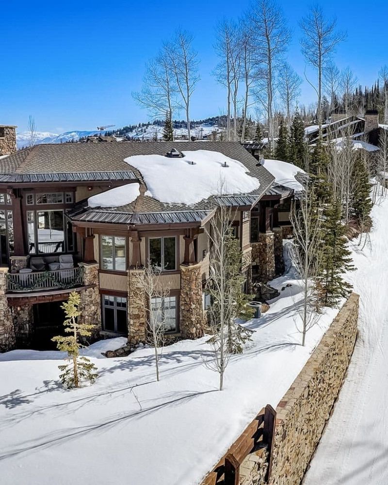 Aerial view of stone-and-timber Park City home surrounded by snow and aspens
