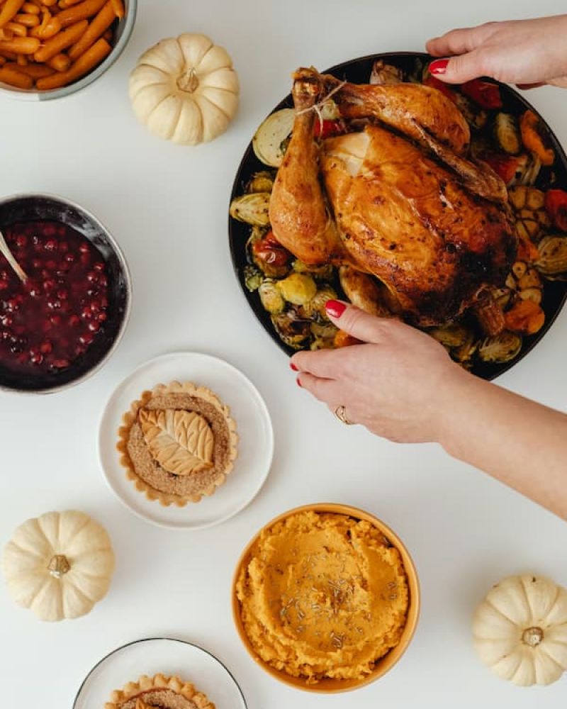 Overhead view of roast turkey, cranberry sauce, and side dishes on a white table