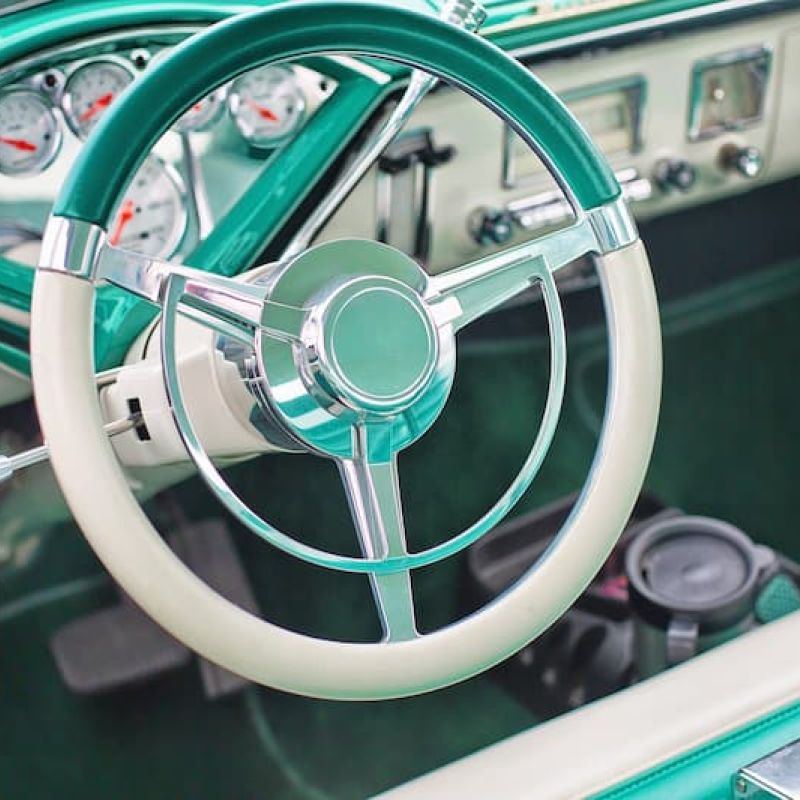 Teal vintage car interior with chrome steering wheel and gauge cluster