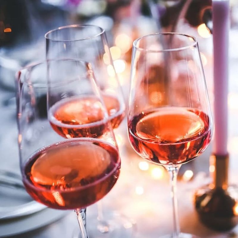 Three glasses of rose wine on a candlelit holiday table