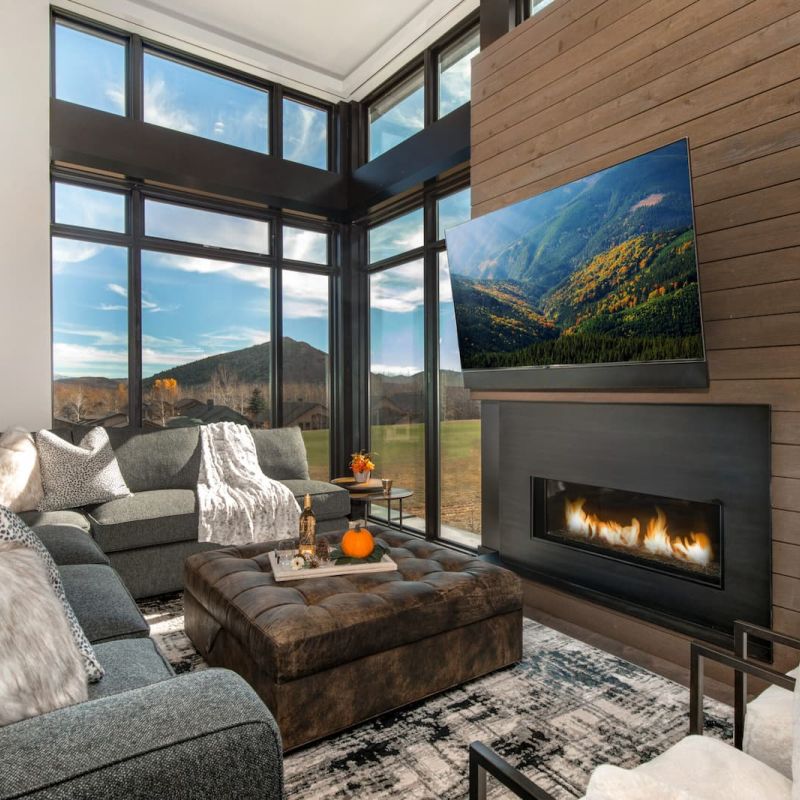 Modern living room with linear fireplace and wall TV showing mountain ski slope view