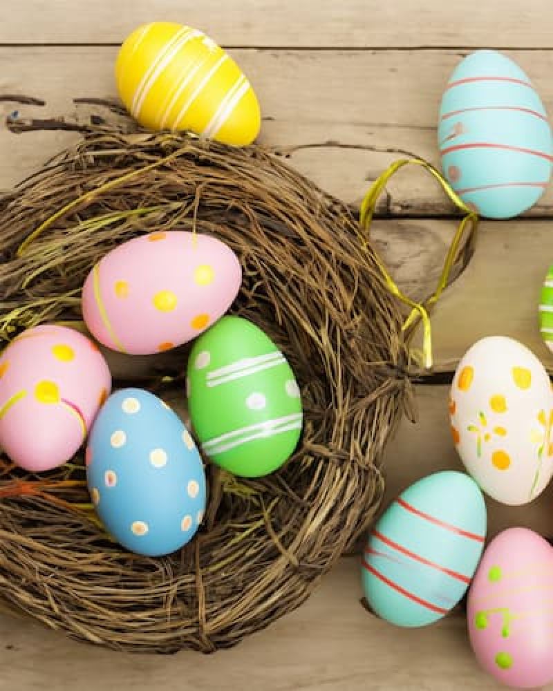 Painted Easter eggs in a woven nest on weathered wood planks