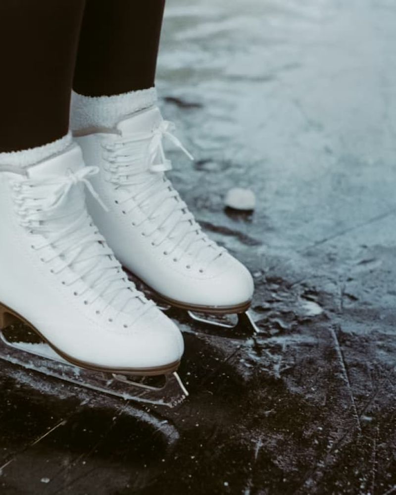 Close-up of white figure skates standing on scratched ice