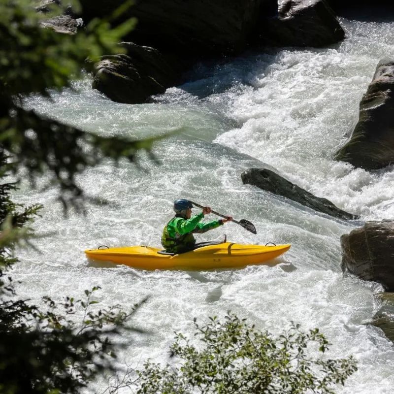 Solo whitewater kayaker navigating a rocky rapid in a yellow boat