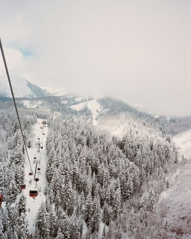 Aerial view of a snow-covered ski resort with gondolas descending forested slopes