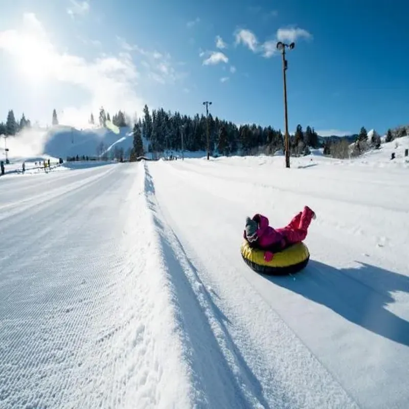 Child sliding down a groomed snow tubing lane on a yellow tube