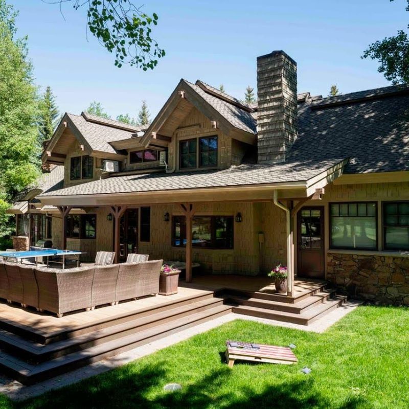 Rear exterior of a shingled home with covered deck and lawn games