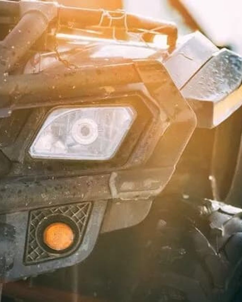 Close-up of a UTV front headlight and bumper in winter sun