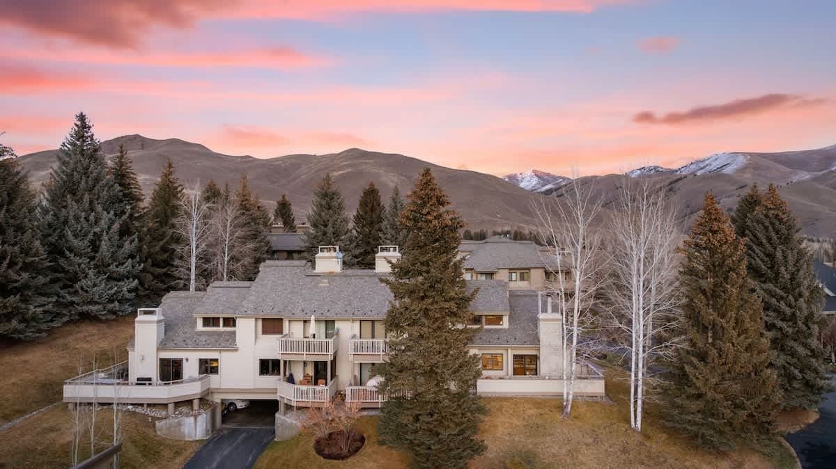 Aerial view of a multi-level mountain home at sunset with peaks behind