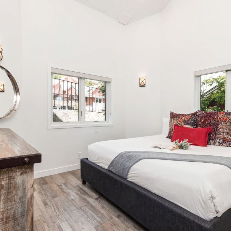 Bedroom with king bed, patterned pillows, mounted TV, and round mirror