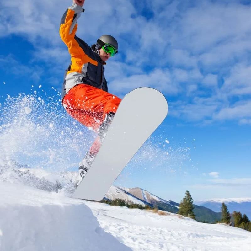 Snowboarder catching air with snow spray against a blue sky