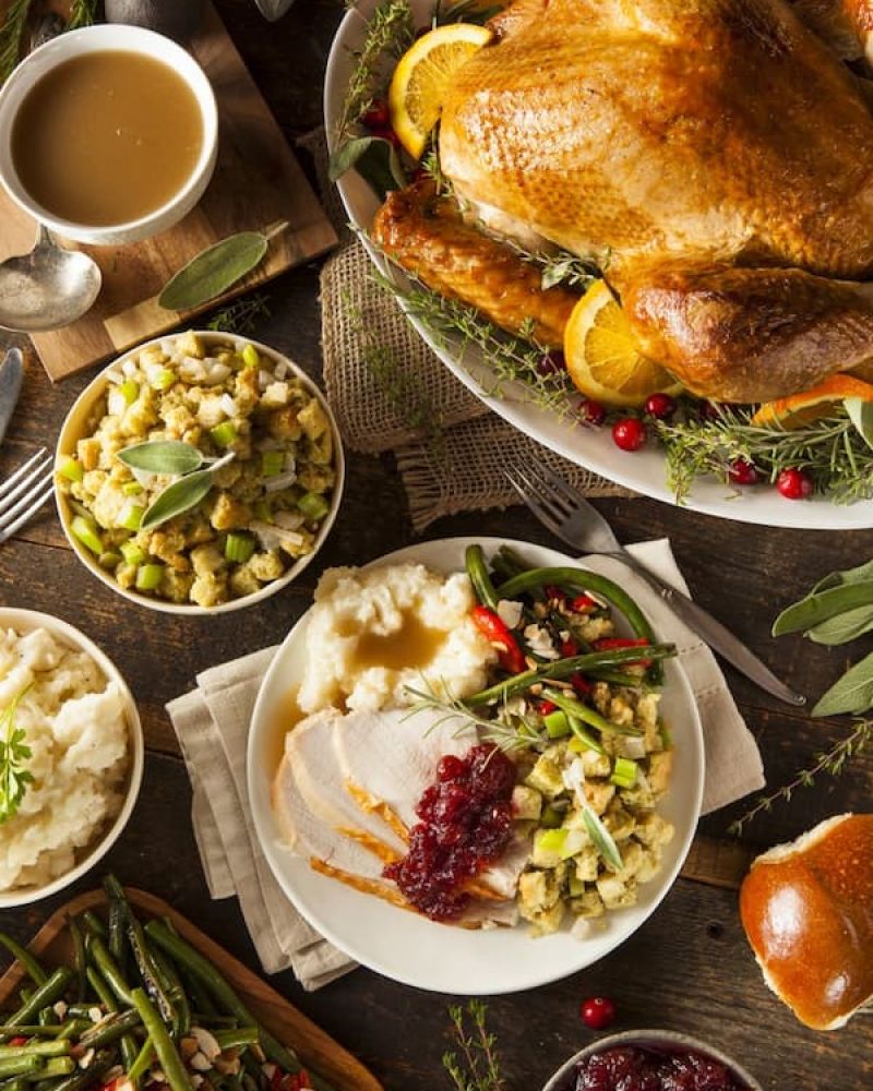 Thanksgiving table with roast turkey, mashed potatoes, stuffing, gravy, and cranberry sauce
