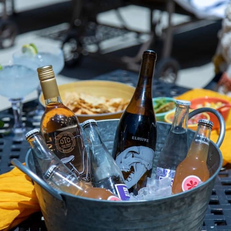 Metal bucket of chilled wine and beer bottles on a patio table