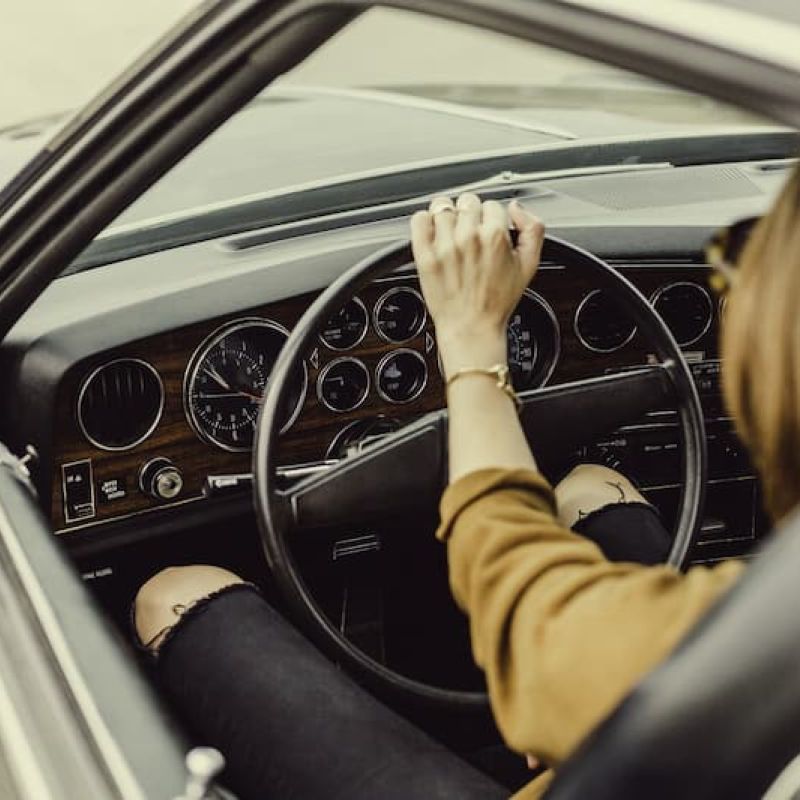 Driver behind the wheel of a vintage car with wood-grain dashboard