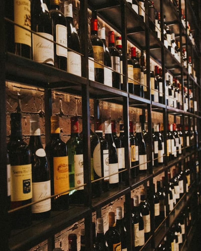 Wall of wine bottles stacked floor to ceiling on illuminated wooden shelves