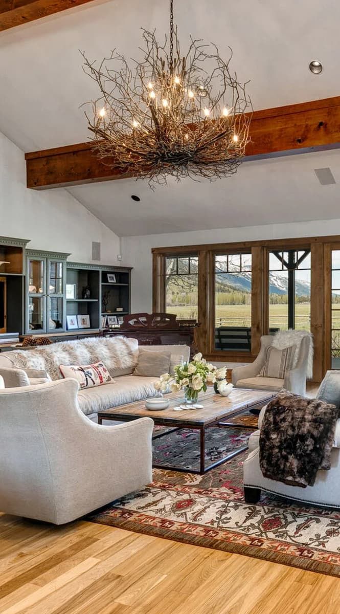Living room with twig chandelier, vaulted beamed ceiling, and meadow view
