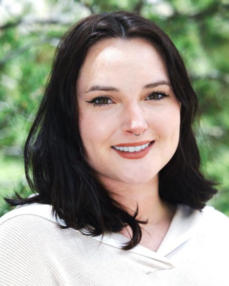 Headshot of a smiling woman with dark hair and a cream sweater