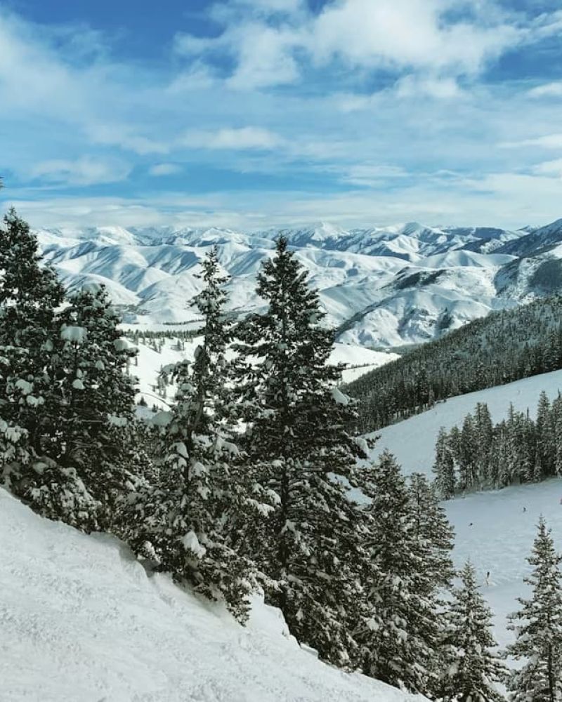 View from a snowy ski run over forested mountains and valleys