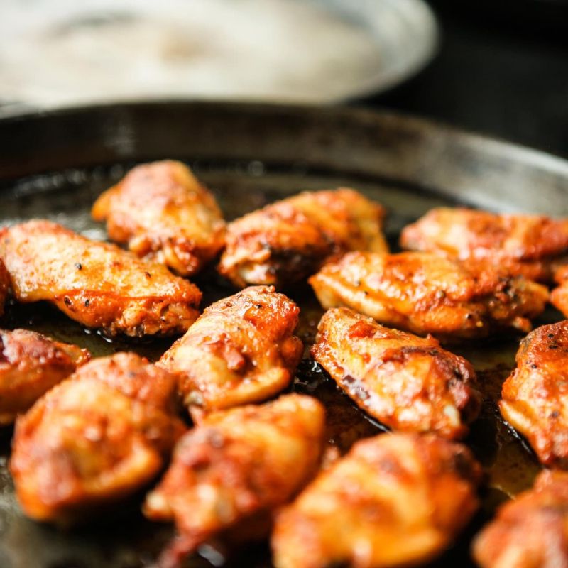 Roasted chicken wings tossed in red sauce on a platter