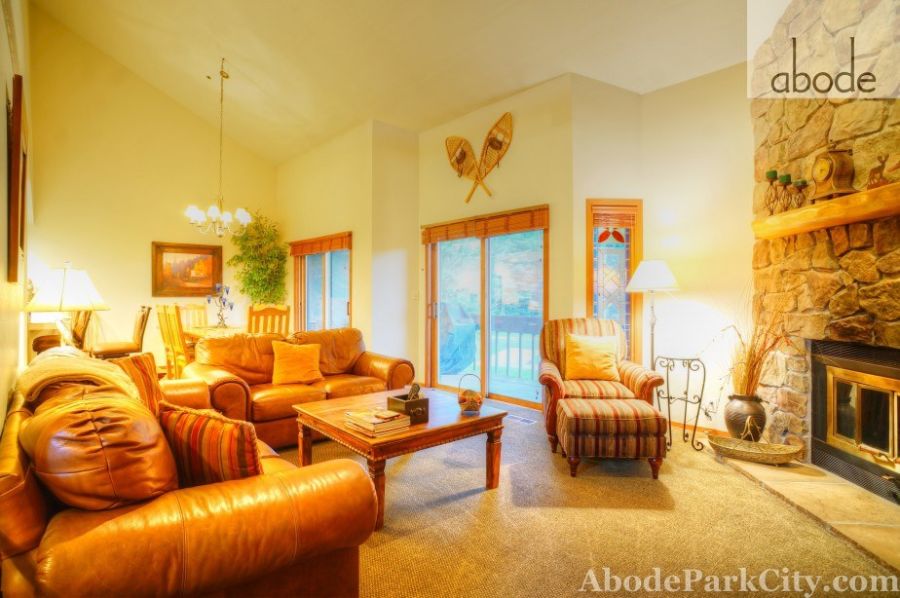 Living room with leather sofas, vaulted ceiling, and stone fireplace
