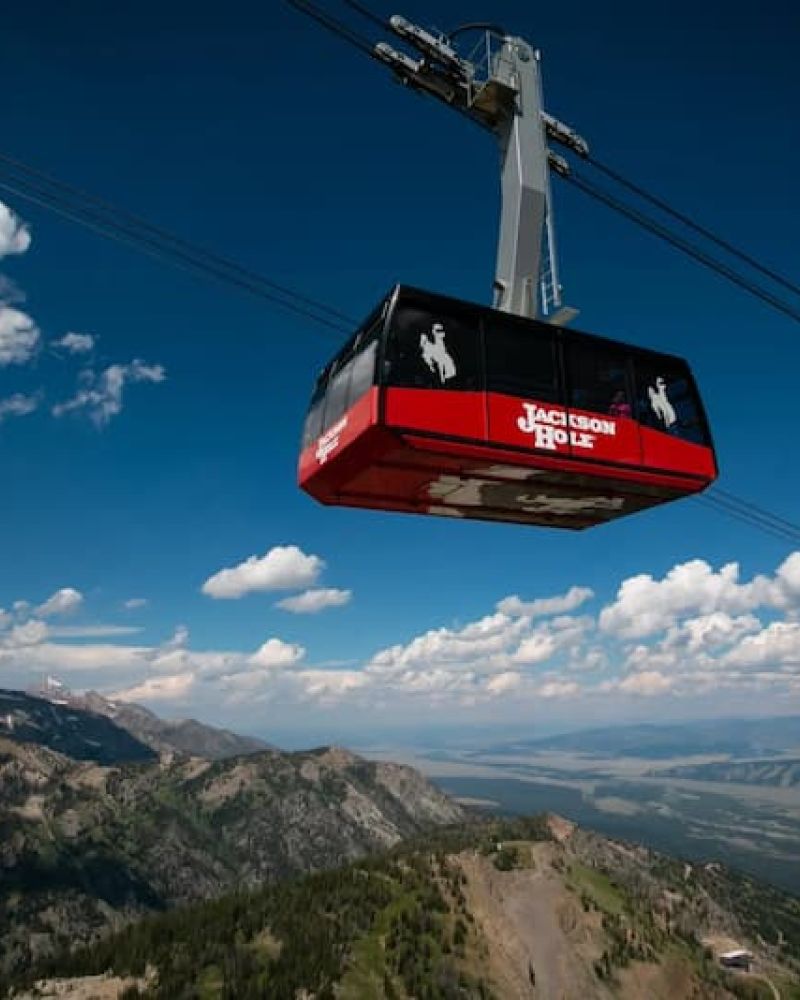Red Jackson Hole aerial tram car suspended above mountains and valley