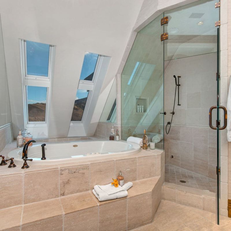 Bathroom with skylight windows, soaking tub, and glass-enclosed shower